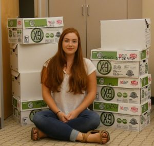 A student sitting in front of stacked boxes containing poetry