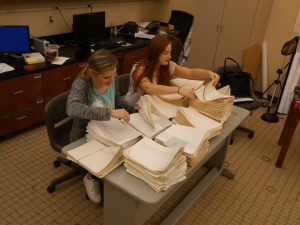 Two students flipping through piles of Justiss' work